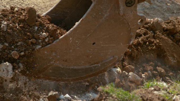 特写，dop: 大型液压推土机铲斗装载沉重的岩石和土壤。
