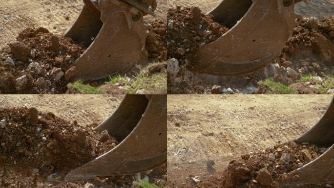 特写，dop: 大型液压推土机铲斗装载沉重的岩石和土壤。