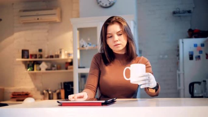 一位女士用仿生手从杯子里喝酒并操作平板电脑