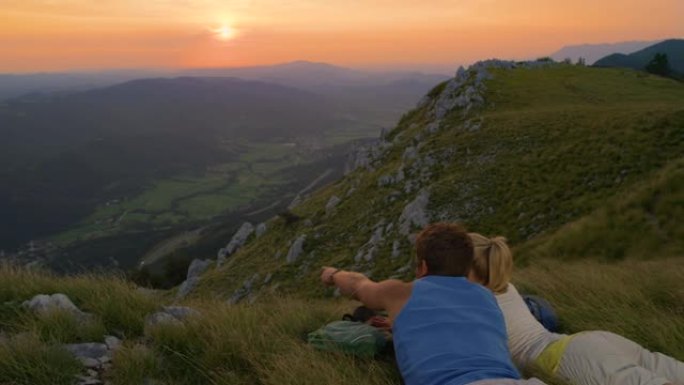 慢动作: 活跃的男女在日落时观察风景如画的山脉。