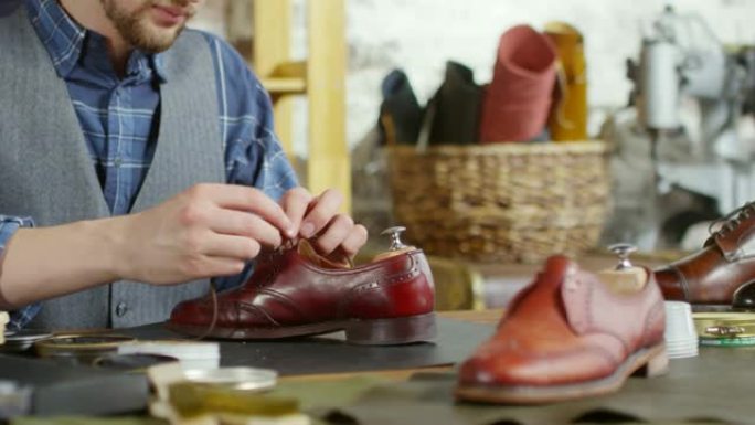 专业鞋匠在修理过的靴子上系鞋带