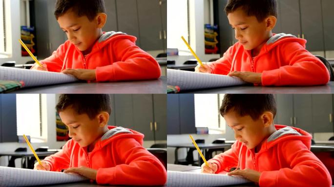 专注的亚洲男生在学校4k教室的书桌上学习的前视图