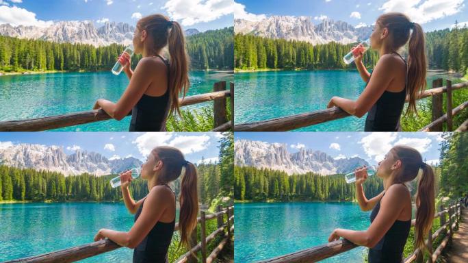 女人在山湖放松，用可重复使用的水瓶喝水