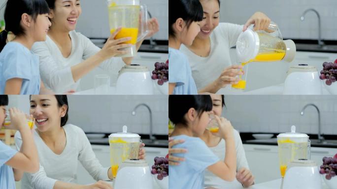 美丽的母亲和漂亮的女儿喝橙汁。泰国的家庭。