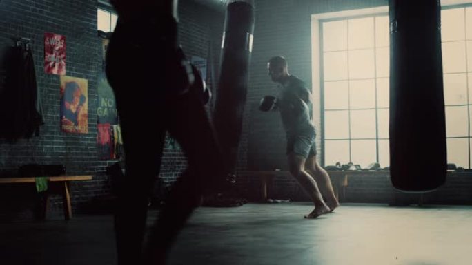 强壮英俊的男性跆拳道运动员正在阁楼健身房锻炼身体，墙上贴着励志海报。男性运动员正在拳击袋上练习拳击。