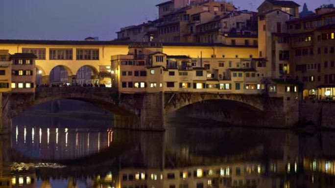 意大利佛罗伦萨。晚上韦基奥桥全景。夜灯在阿诺河的水域中反射。佛罗伦萨位于托斯卡纳大区。平移镜头，4K