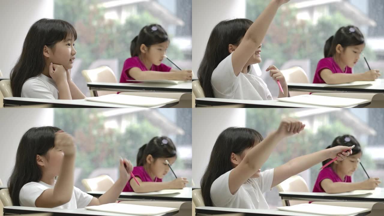 亚洲小女孩举起手臂回答教室老师的问题。幼儿园学前概念。