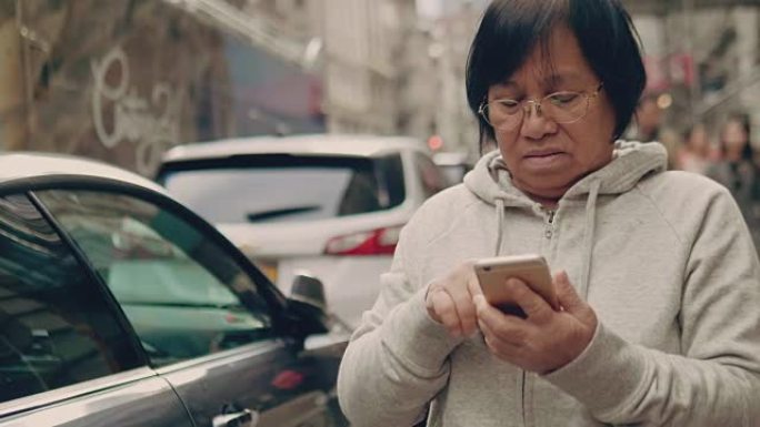 亚洲老年人站在城市，使用智能手机。