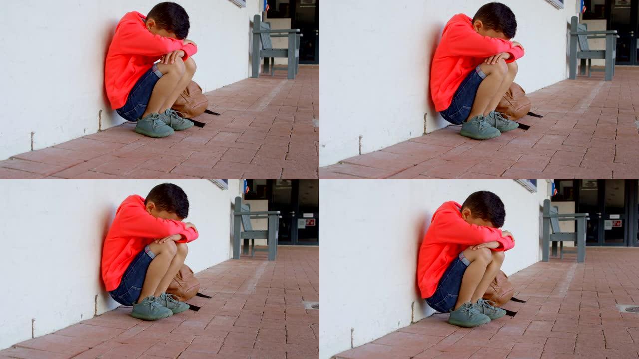 亚洲男生的侧视图，头朝下独自坐在学校4k走廊的地板上