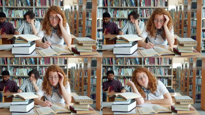 疲惫的红发女孩在图书馆学习，然后睡在桌子上在室内放松