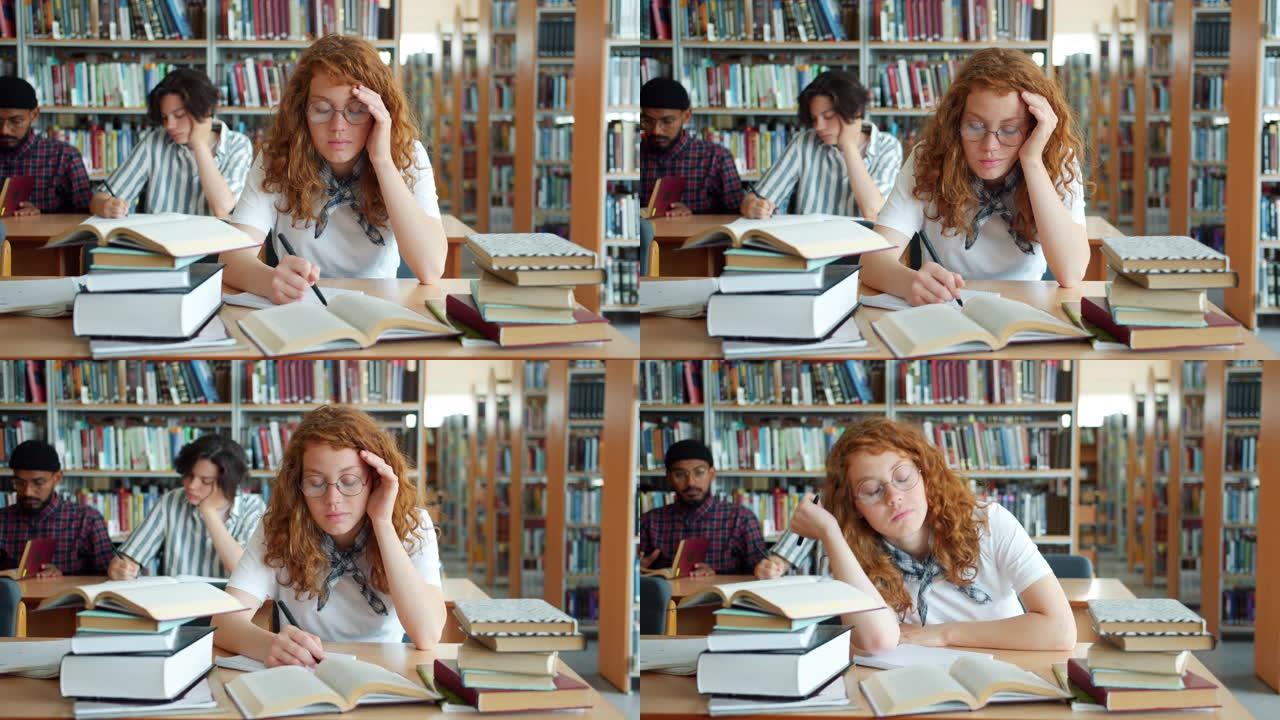 疲惫的红发女孩在图书馆学习，然后睡在桌子上在室内放松