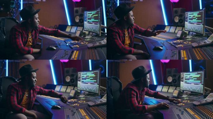 时尚的音频工程师在音乐录音棚工作，使用调音板和软件来创作现代热门歌曲。创意黑人艺术家音乐家在办公桌控