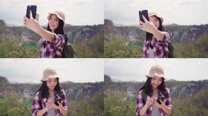 亚洲背包客女人在山顶上自拍，年轻女性快乐地用手机自拍享受假期徒步旅行冒险。生活方式女性旅行和放松概念