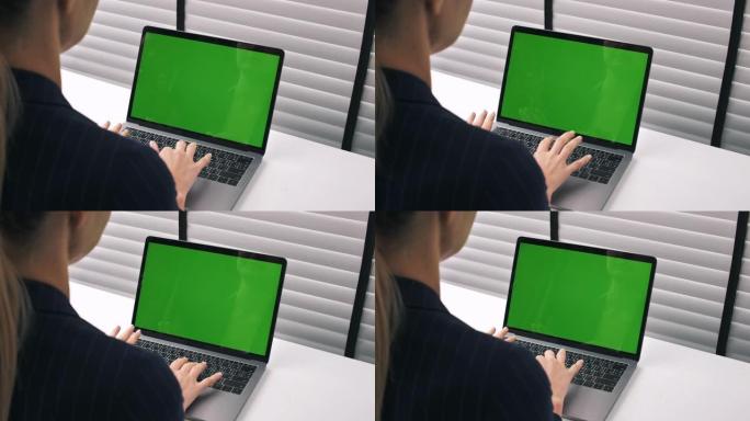 女商人在办公室带有绿屏的笔记本电脑上工作
