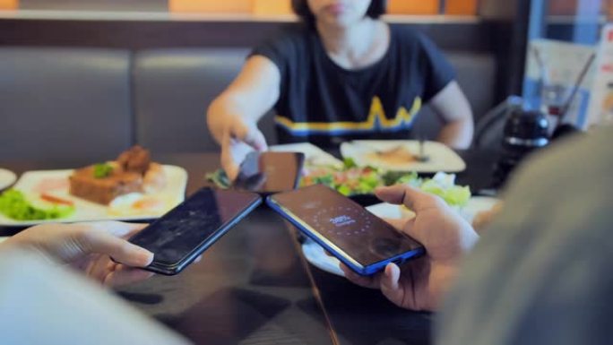 人们在餐厅通过无线共享智能手机充电。手机电池无线充电共享技术。无线充电共享智能手机。技术，人，生活方