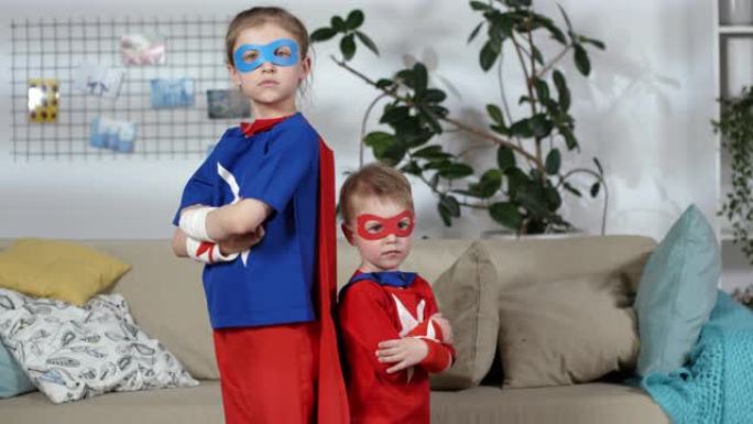 穿着超级英雄服装的小男孩和女孩摆姿势拍照