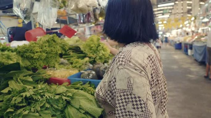 购买水果和蔬菜的亚洲高级妇女站在农贸市场