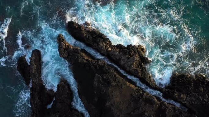 俯视海浪在岩石海岸线上撞击的抽象鸟瞰图