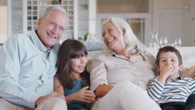 微笑的祖父母与孙子坐在沙发上的肖像