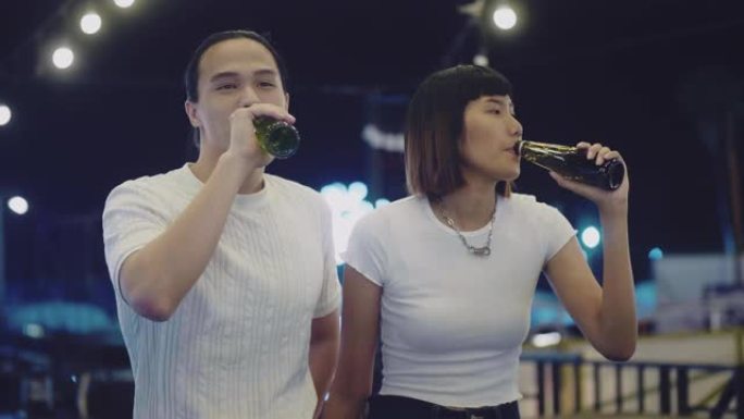 年轻的亚洲夫妇在屋顶派对上用啤酒敬酒