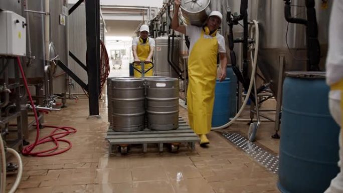 拉丁美洲操作员在一家啤酒厂拉着带有4个啤酒桶的手动叉车