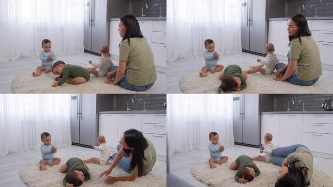 快乐的亚洲女人带着婴儿三胞胎在地毯上放松