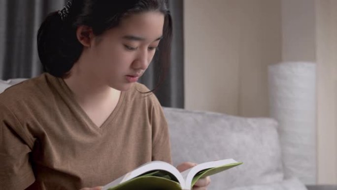 亚洲少女在家时读一本非小说类书籍。她翻开学习书的一页。学习绿色教育的女孩。