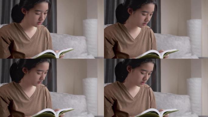 亚洲少女在家时读一本非小说类书籍。她翻开学习书的一页。学习绿色教育的女孩。