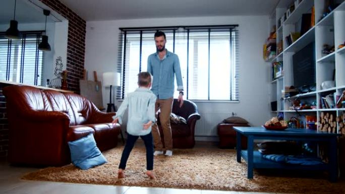 快乐的年轻开朗的高加索父亲和小儿子在现代住宅客厅慢动作中一起跳舞很开心。