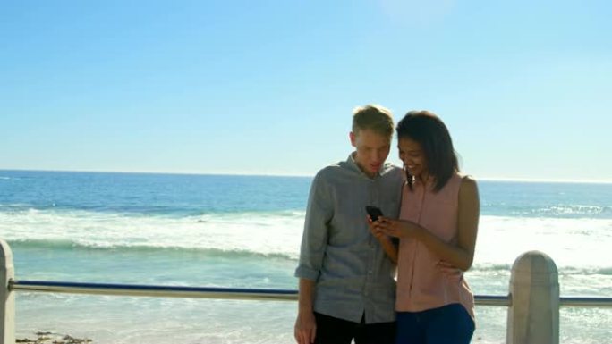 快乐的年轻夫妇在栏杆附近使用手机4k