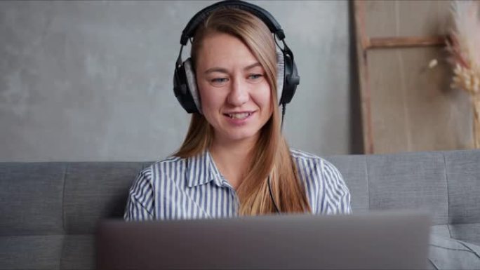 在家研究古兰经。快乐的年轻积极的金发女人使用笔记本电脑视频电话进行电子学习。