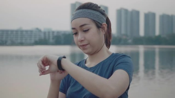 亚洲妇女早上在智能手表上监视自己的跑步表现