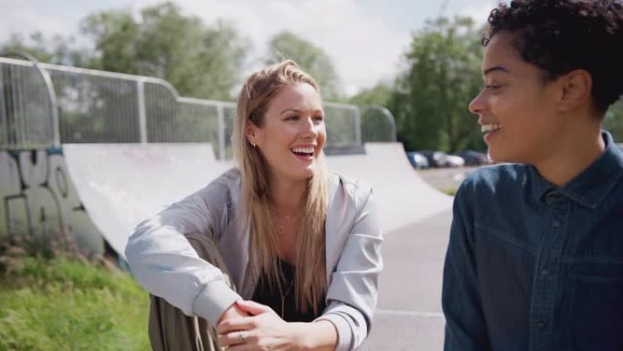 两个女性朋友在城市溜冰鞋公园里说笑