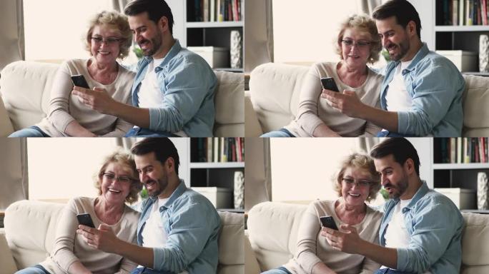 年幼的儿子与成熟的妈妈一起使用智能手机展示有趣的照片
