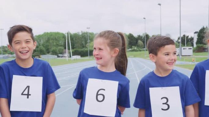 运动日在田径跑道上戴着竞争对手号码的儿童肖像