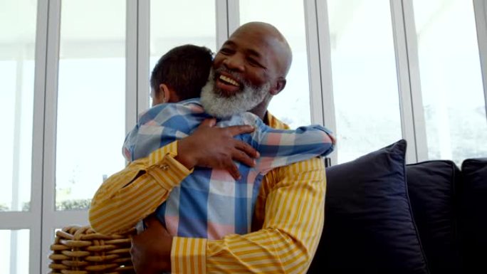 成熟的黑人父亲在舒适的家庭4k客厅拥抱儿子的前视图