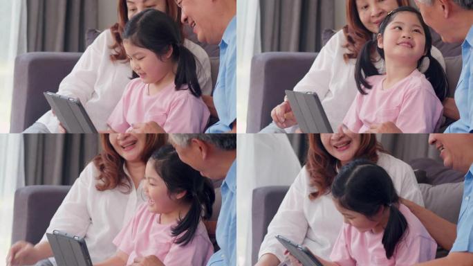 亚洲祖父母和孙女在家里使用平板电脑。中国老年人，爷爷和奶奶快乐度过家庭与年轻女孩一起放松社交媒体，躺