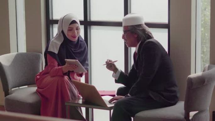 穆斯林人在咖啡店里用平板电脑和笔记本电脑工作和讨论。
