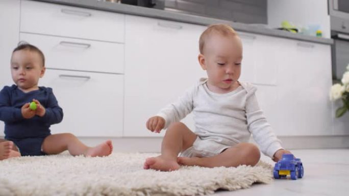 蹒跚学步的三胞胎在家里的地毯上玩耍