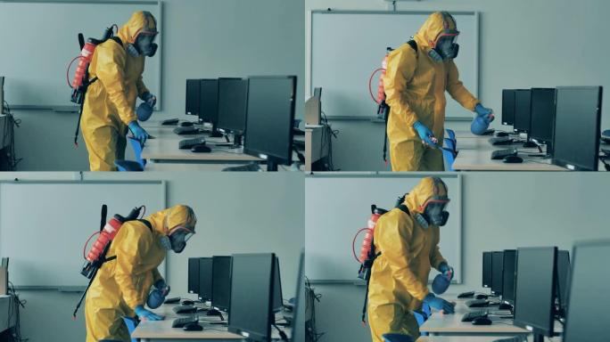 一个穿着危险品套装的男人正在给计算机课消毒