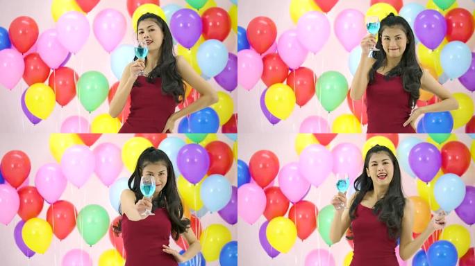 美丽的亚洲女人在派对上以慢动作带着快乐的情感跳舞，彩色气球背景。