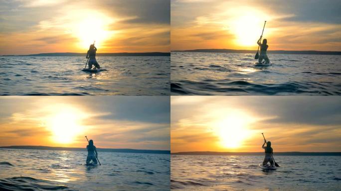 女运动员漂浮在特殊的木板上，在日落背景上划桨。4K。