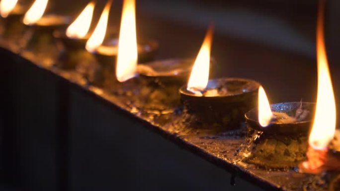 宏观: 美丽的火焰在寺庙的小油蜡烛内闪烁