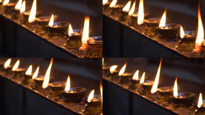 宏观: 美丽的火焰在寺庙的小油蜡烛内闪烁