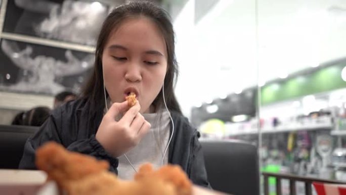 年轻漂亮的女孩在快餐店吃炸鸡