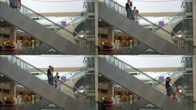 购物中心的拉丁美洲家庭在自动扶梯上下降，而小女孩则讲话并指出