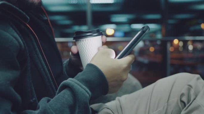 时髦的人使用社交媒体和智能手机，并在机场拿着咖啡杯。