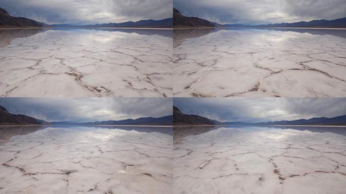 在死亡谷国家公园的Badwater盆地中，水飞越盐壳层的镜面。美国加利福尼亚州。