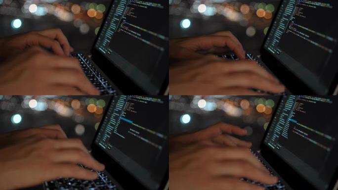 程序员以美丽的夜窗为背景编写网站开发代码，在夜窗中，在散焦中可以看到城市的灯光。