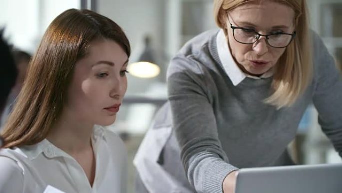 与年轻女士一起在笔记本电脑上工作的女商业导师